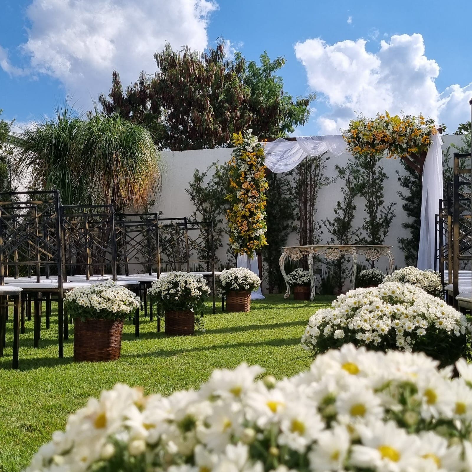 Cerimônia ao ar livre no Espaço Matos em Lagoa Santa, com arco floral, cadeiras tiffany e arranjos de margaridas brancas